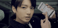a young man is holding a cell phone in his hand .