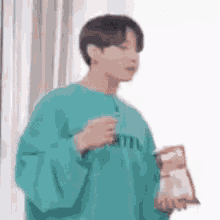 a young man in a blue sweater is holding a bag of chips and a drink .