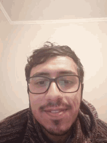 a man wearing glasses and a sweater smiles for the camera