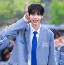 a young man wearing a suit and tie is smiling and adjusting his hair .