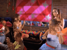 a group of people are gathered in a room with a pink and red wall