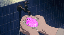 a person is holding a pink frog under a faucet in their hands