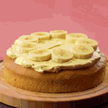 a cake with banana slices on top of it on a wooden cutting board