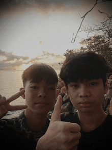 two young boys are giving a thumbs up sign