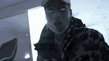 a man wearing a hat and a mask is smoking a cigarette .