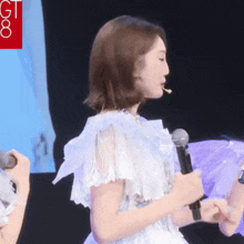 a woman in a white dress is holding a microphone with the letters gt on it