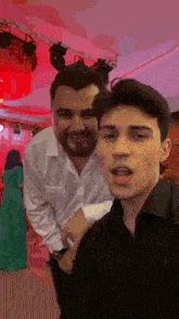 a man with a beard is standing next to a young man who is taking a selfie .