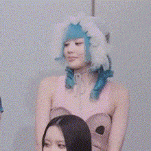 a woman with blue hair is wearing a pink top and a white hat .