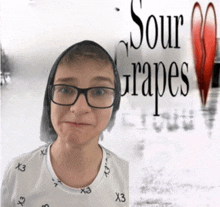 a boy wearing glasses stands in front of a poster for sour grapes