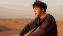 a young man is sitting in the middle of a desert .
