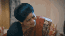 a woman in a saree is smiling and talking to another woman .