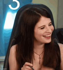 a woman is sitting in a chair and smiling with the number 3 in the background