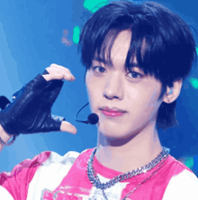 a young man wearing a pink and white striped shirt is holding a microphone in front of his face