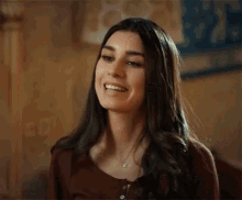 a woman is smiling and looking at the camera while sitting at a table .