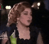 a woman in a black dress is holding a green drink with a straw .