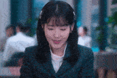 a woman in a suit is smiling and looking down