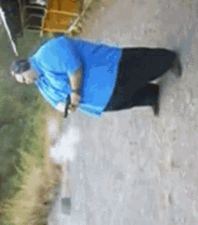 a man in a blue shirt is kneeling down on a dirt path