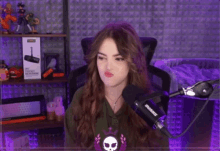 a woman sitting in front of a shure microphone making a face