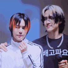 two young men are standing next to each other and one of them is wearing a shirt that says ' 배고파오 ' on it