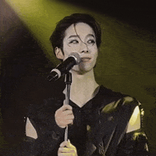 a woman singing into a microphone with a yellow light in the background