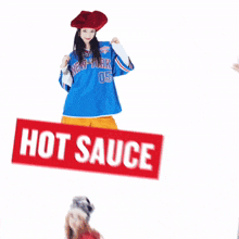 a woman wearing a blue new york jersey is standing next to a red sign that says hot sauce