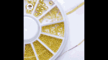 a white container filled with different types of gold beads and rhinestones