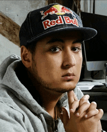 a man wearing a red bull hat looks serious
