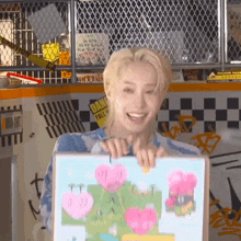 a young man is holding a picture frame with a drawing of hearts on it and smiling .