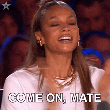 a woman is clapping and smiling with the words come on mate written below her