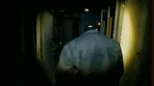 a man in a hooded jacket is walking through a dark room .