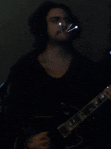 a man in a black shirt is playing an electric guitar