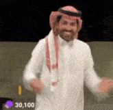 a man in a white shirt and red scarf is dancing in front of a wall .