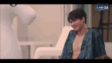 a shirtless man in a blue robe is sitting next to a white unicorn .