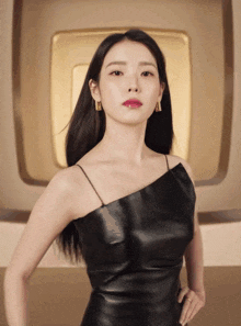 a woman in a black leather dress is standing with her hand on her hip