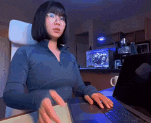 a woman wearing glasses is typing on a laptop computer