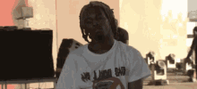 a man with dreadlocks wearing a white shirt that says no judge sad
