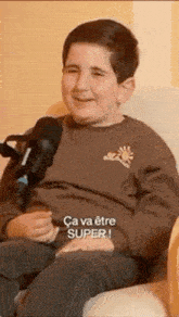 a young boy is sitting in a chair with a microphone in front of him .
