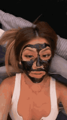 a woman with a black mask on her face is laying on a bed