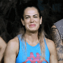 a woman in a blue kappa tank top smiles