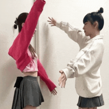 a girl in a pink sweater is standing next to another girl in a white shirt