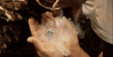 a person is holding a ring in their hands with smoke coming out of it .