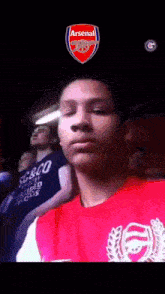 a man wearing a red shirt with the word arsenal on the front