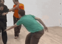 a man in a green shirt is being held by two other men