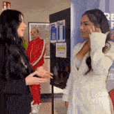 two women are standing next to each other in front of a bulletin board with a sign on it that says " please wait here "