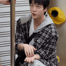 a young man wearing a plaid shirt with the letter o on the sleeve