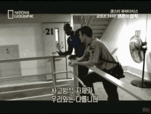 a man in a blue shirt is being escorted by two police officers in front of a door that has the number 21 on it