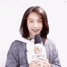 a man with long hair is holding a microphone with a tv logo on it