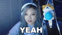 a woman is wearing headphones and holding a stuffed animal while playing a video game .