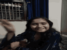 a girl with a blue shirt on is smiling and waving