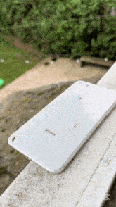 a white iphone with a cracked screen is laying on a balcony